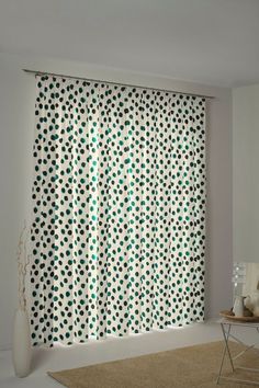 a white and green polka dot curtain in a living room with a rug on the floor