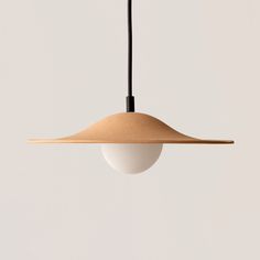 a light hanging from a ceiling with a white wall behind it and a black cord on the end