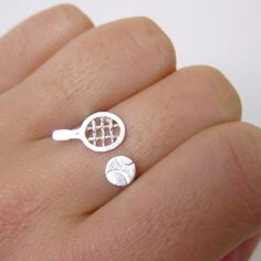 a person's hand holding a tennis racket and ball ring