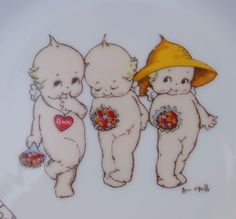 three little babies with hats and flowers on them are standing in front of a plate