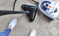 a person vacuuming the carpet with a cordless mop next to an iron