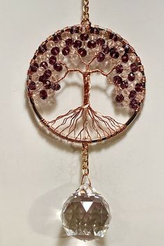 a tree of life pendant is hanging on a white wall with a brown bead around it