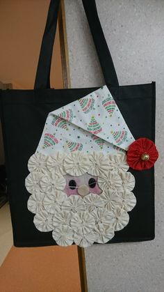 a black bag with paper flowers and a santa clause face on the front, along with a red flower