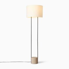 a floor lamp with a white shade on the base and a black cord attached to it