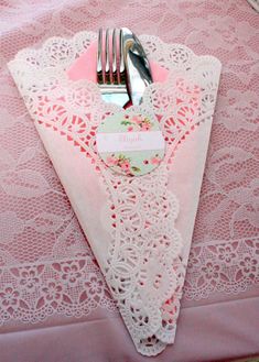 a pink table cloth with a white lace border and a fork and knife on it