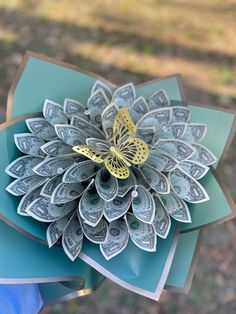 an origami flower made out of dollar bills with a butterfly sitting on top