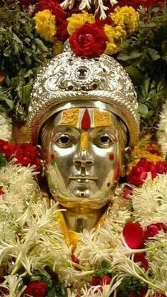 a golden statue with flowers around it and a crown on top of it's head