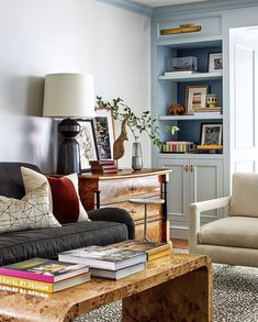 a living room filled with furniture next to a book shelf and a lamp on top of a coffee table