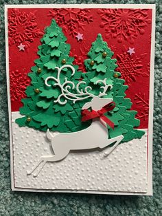 a handmade christmas card with a deer and tree on the front, red background