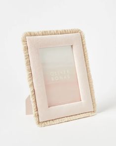 a pink and white photo frame sitting on top of a table