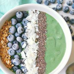 a bowl filled with green smoothie, blueberries and granola on top of it