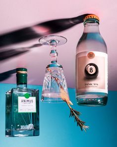 two bottles of gin and an empty glass bottle hanging from a ceiling fan on a blue wall