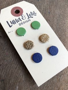 three pairs of blue, green and gold studs on a white card with a tag