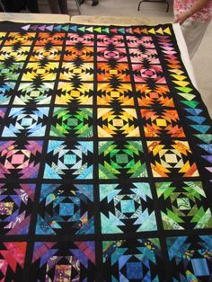 a colorful quilt is displayed on a bed