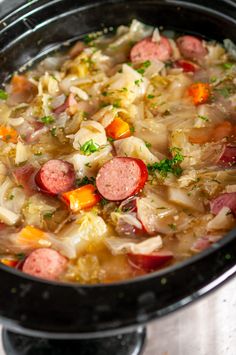 a pot filled with soup and sausages on top of a stove