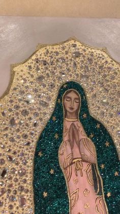 an image of the virgin mary in gold and green glitters on a white background