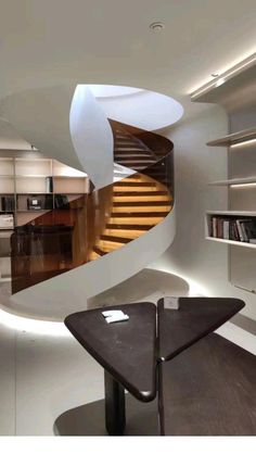 a spiral staircase in the middle of a room with bookshelves on either side