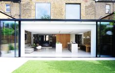 an open living room and dining area in front of a large brick building with glass walls