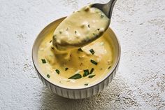 a spoon full of cheese sauce in a bowl