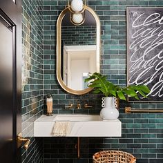 a bathroom with green tiled walls and gold trimmings, a mirror above the sink