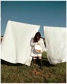 a woman holding a plate in front of some white cloths