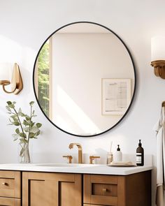 a bathroom with a large round mirror above the sink and wooden cabinets below it,