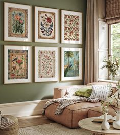 a living room with green walls and pictures on the wall above the couch, along with vases filled with flowers