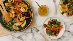 two white plates with salad on them next to silverware