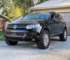 a black volkswagen suv parked in front of a house