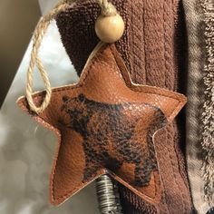 a brown leather star ornament hanging from a hook on a towel with a wooden bead