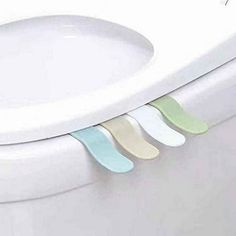 three pieces of toilet paper are attached to the rim of a toilet bowl lid with four different colored strips hanging from it