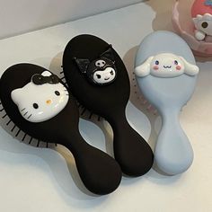 three black and white hairbrushes with hello kitty faces on each one's head