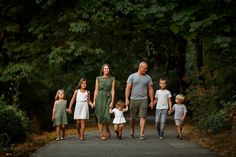 a family walking down a path in the woods holding hands and looking at the camera