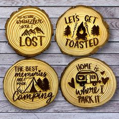 four wood burned coasters with camping sayings on the front and back, sitting on top of a wooden table