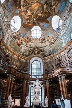 the interior of a library with many bookshelves and statues