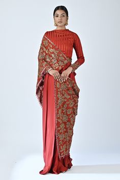 Red saree gown with pleated cowl drapes, stripe pattern yoke, leaf pattern Ajrakh print, cut dana, zardozi and nakshi hand embroidered pallu and sleeve cuffs.
Components: 1
Pattern: Printed and Hand Embroidered
Type Of Work: Ajrakh Print, Cut Dana, Zardozi and Nakshi Work
Neckline: Boat Neck
Sleeve Type: Full Sleeves
Fabric: German Satin, Crepe
Color: Red
Other Details: 
Printed inner panel on pallu
Embroidered waistband
Bead tasselled border on pallu
Attached lining
Closure: Back concealed zip Draped Saree Gown, Gown Saree, Corset Draping, Full Sleeve Gowns, Drape Gown, Saree Gowns, Draped Saree, Gown Gold, Zardozi Work