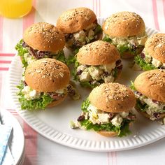 small sandwiches are arranged on a white plate with red and white checkered tablecloth