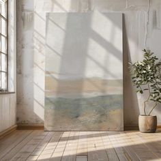 an empty room with a painting on the wall and a potted plant next to it