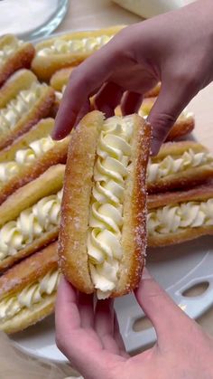 a person holding a pastry in front of other desserts on a plate with white icing