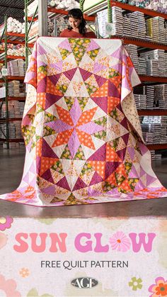 a woman is holding up a quilt in the sunglow store with other items behind her