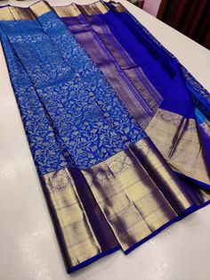 blue and gold saree laying on top of a white table with an intricate design