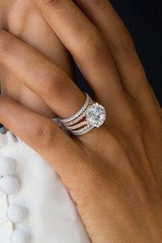 a woman's hand with two diamond rings on her left and the other hand holding an engagement ring