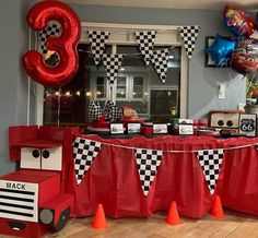 a birthday party with cars and balloons on the wall, table cloths and decorations