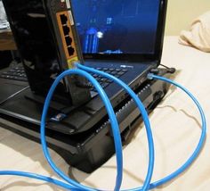 an open laptop computer sitting on top of a bed next to a blue hose connected to it