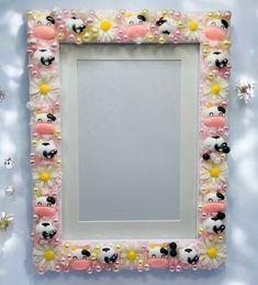 a pink frame with white flowers and panda bears on the front is surrounded by pearls