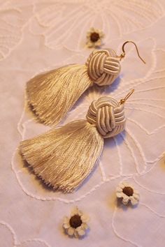 two pairs of tasseled earrings sitting on top of a doily covered table