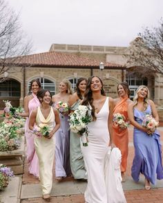 a group of women standing next to each other in front of a building with flowers