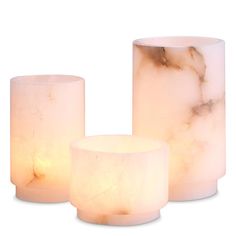 three white marbled candles with one lit and the other turned on in different directions