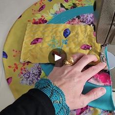 a person is working on a piece of fabric with scissors and sewing machine in the background