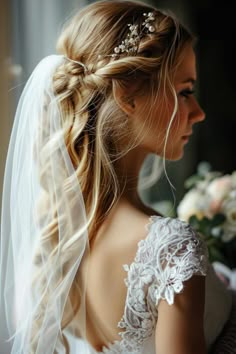 a woman in a wedding dress with a veil on her head and flowers in her hair